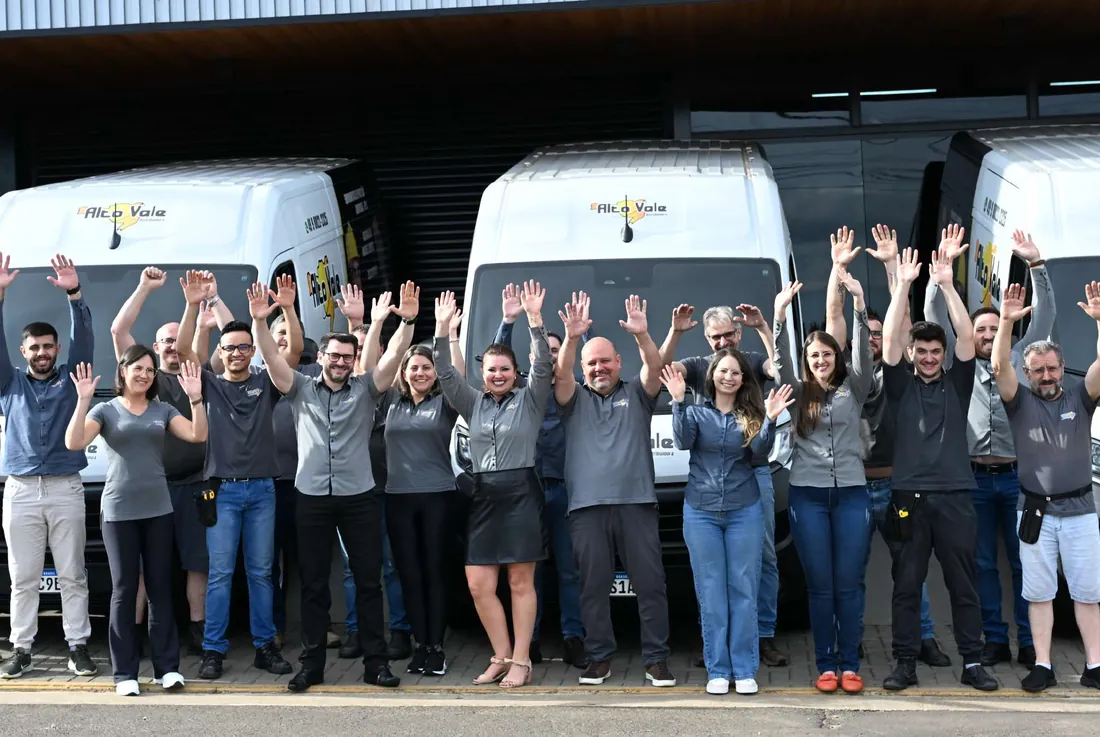 Equipe da Distribuidora Alto Vale em frente à matriz, com a frota própria